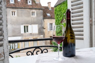 Burgundy şarap bölgesindeki Grand Cru Pinot üzüm bağlarından şarap, cam ve bir şişe kırmızı şarap ve eski kasaba caddesinin görüntüsü Fransa 'nın Burgundy şarap bölgesinde