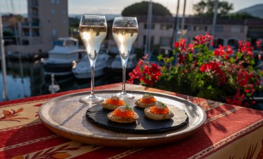 Rus tarzı parti, iki bardak soğuk şampanya, kırmızı havyarlı bulanık ve Saint-Tropez yakınlarındaki Port Grimaud manzaralı, yazın Fransız Riviera 'sında tatiller.