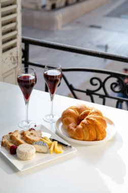 Kir Royal içen, Fransız aperatifi. Krema ve şampanyayla kaplanmış, genellikle flüt bardaklarıyla servis edilen, eski Fransız köyü manzaralı.