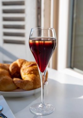 Kir Royal içen, Fransız aperatifi. Krema ve şampanyayla kaplanmış, genellikle flüt bardaklarıyla servis edilen, eski Fransız köyü manzaralı.
