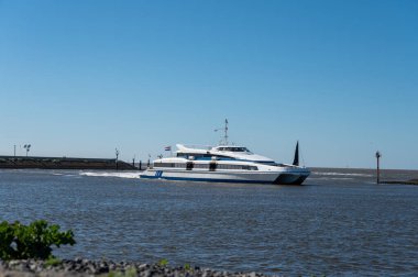 Hollanda, Friesland, Wadden Denizi 'ndeki Harlingen balıkçı kasabasının sahilinde yürüyorum.
