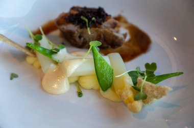 Kızarmış sığır filetosu, beyaz kuşkonmaz ve bezelye ile servis ediliyor.