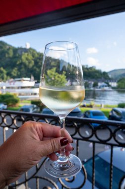 Mosel şarap bölgesinde açık havada servis edilen beyaz kaliteli şarap kadehiyle el ele tutuştuk. Mosel nehri ve eski Alman kasabası güneşli bir günde, Almanya 'da arka planda yer aldı.