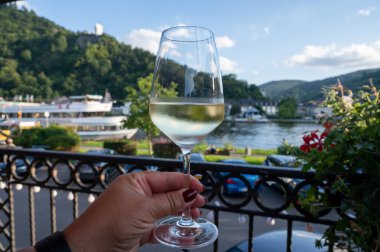 Mosel şarap bölgesinde açık havada servis edilen beyaz kaliteli şarap kadehiyle el ele tutuştuk. Mosel nehri ve eski Alman kasabası güneşli bir günde, Almanya 'da arka planda yer aldı.