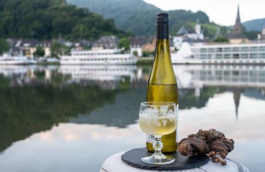 Mosel şarap bölgesinde beyaz kaliteli riesling şarabı tatmak için Mosel nehri ve Almanya 'nın güneşli günlerinde arka planda kalan eski Alman kasabası ile birlikte açık havada servis edilir.
