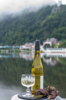 Mosel şarap bölgesinde beyaz kaliteli riesling şarabı tatmak için Mosel nehri ve Almanya 'nın güneşli günlerinde arka planda kalan eski Alman kasabası ile birlikte açık havada servis edilir.