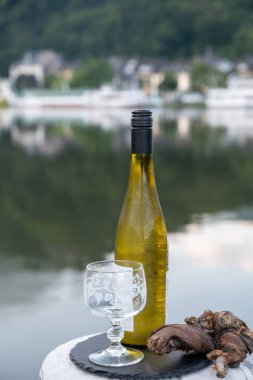 Mosel şarap bölgesinde beyaz kaliteli riesling şarabı tatmak için Mosel nehri ve Almanya 'nın güneşli günlerinde arka planda kalan eski Alman kasabası ile birlikte açık havada servis edilir.