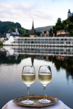 Mosel şarap bölgesinde beyaz kaliteli riesling şarabı tatmak için Mosel nehri ve Almanya 'nın güneşli günlerinde arka planda kalan eski Alman kasabası ile birlikte açık havada servis edilir.