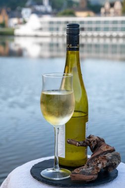 Mosel şarap bölgesinde beyaz kaliteli riesling şarabı tatmak için Mosel nehri ve Almanya 'nın güneşli günlerinde arka planda kalan eski Alman kasabası ile birlikte açık havada servis edilir.
