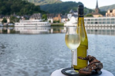 Mosel şarap bölgesinde beyaz kaliteli riesling şarabı tatmak için Mosel nehri ve Almanya 'nın güneşli günlerinde arka planda kalan eski Alman kasabası ile birlikte açık havada servis edilir.