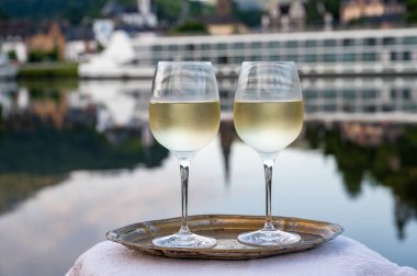 Mosel şarap bölgesinde beyaz kaliteli riesling şarabı tatmak için Mosel nehri ve Almanya 'nın güneşli günlerinde arka planda kalan eski Alman kasabası ile birlikte açık havada servis edilir.