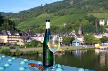 Yeşil şişeli beyaz kaliteli şarap, güneşli bir günde Mosel Nehri 'nin karşısındaki eski köprüde servis edilir.