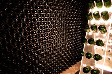 Derin ve uzun yeraltı mağaralarındaki raflarda şişeler şarap ve üzüm şarabından şampanya yapıyor Reims, Champagne, France 'ta.