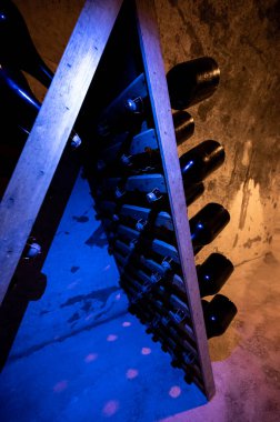 Derin ve uzun yeraltı mağaralarındaki raflarda şişeler şarap ve üzüm şarabından şampanya yapıyor Reims, Champagne, France 'ta.