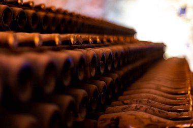 Derin ve uzun yeraltı mağaralarındaki raflarda tozlu şişeler, Reims, Champagne, Fransa 'da şarap ve noir üzümlerden şampanya yapıyor.