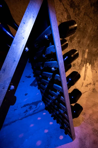 Derin ve uzun yeraltı mağaralarındaki raflarda şişeler şarap ve üzüm şarabından şampanya yapıyor Reims, Champagne, France 'ta.