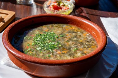 Tenerife 'deki tipik bir Kanarya Adası işletmesi olan Guachinche' de akşam yemeği, yerel olarak üretilen beyaz veya kırmızı şarap ile birlikte güneşli bir günde ev yapımı geleneksel yemekler sunuluyor, gofio ile sebze çorbası.