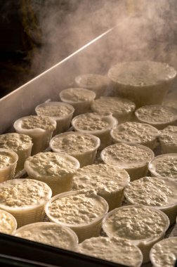 İtalya 'nın Parma kentindeki küçük peynir çiftliğinde sabahın erken saatlerinde taze, yumuşak ricotta peyniri yapma süreci.