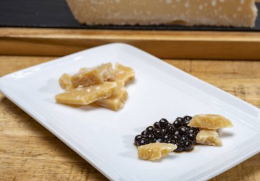 Parma 'dan 72 aylık İtalyan parmegiano-reggiano parmesan peyniri tadı son derece tahıllı ve parçalanmış bir yapısı ve siyah balzamik sirke incileri ile yoğun bir tadı var. Modena' dan DOP, yakın plan.