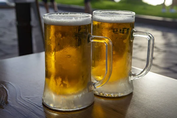 Two pint glasses with cold beer served outdoor on sunset