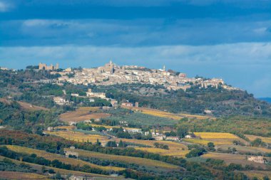 İtalya, Tuscany, Montepulciano yakınlarındaki Val d 'Orcia tepelerinde sabah yürüyüşü. Selvi ağaçları, üzüm bağları, ormanlar ve bulutlu sonbaharda sürülen tarlalarla Toskana manzarası.