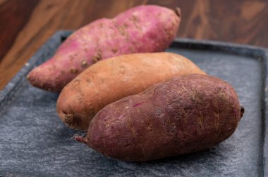 Renkli kök sebzeler pembe, mor ve turuncu organik tatlı patatesler yakın çekim