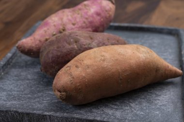 Renkli kök sebzeler pembe, mor ve turuncu organik tatlı patatesler yakın çekim