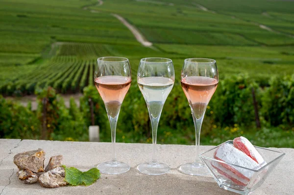 Glasses of white and rose brut champagne wine, firestones from vineyard soil and view on grand cru vineyards of Montagne de Reims near Verzenay, Champagne, France