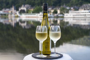 Mosel şarap bölgesinde beyaz kaliteli riesling şarabı tatmak için Mosel nehri ve Almanya 'nın güneşli günlerinde arka planda kalan eski Alman kasabası ile birlikte açık havada servis edilir.