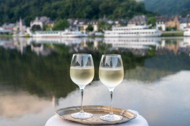 Mosel şarap bölgesinde beyaz kaliteli riesling şarabı tatmak için Mosel nehri ve Almanya 'nın güneşli günlerinde arka planda kalan eski Alman kasabası ile birlikte açık havada servis edilir.