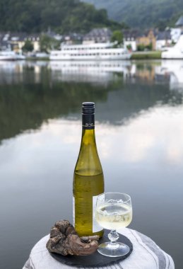 Mosel şarap bölgesinde beyaz kaliteli riesling şarabı tatmak için Mosel nehri ve Almanya 'nın güneşli günlerinde arka planda kalan eski Alman kasabası ile birlikte açık havada servis edilir.