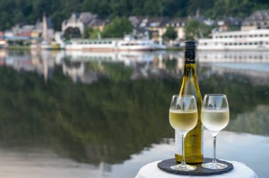 Mosel şarap bölgesinde beyaz kaliteli riesling şarabı tatmak için Mosel nehri ve Almanya 'nın güneşli günlerinde arka planda kalan eski Alman kasabası ile birlikte açık havada servis edilir.