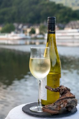 Mosel şarap bölgesinde beyaz kaliteli riesling şarabı tatmak için Mosel nehri ve Almanya 'nın güneşli günlerinde arka planda kalan eski Alman kasabası ile birlikte açık havada servis edilir.