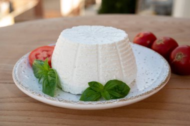 Peynir koleksiyonu, taze domates ve fesleğenle servis edilen yumuşak İtalyan organik peyniri ricotta.