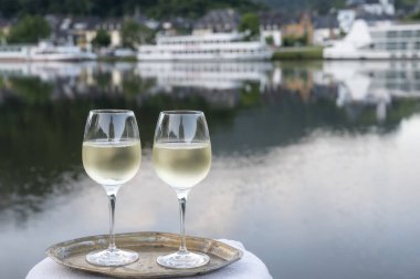 Mosel şarap bölgesinde beyaz kaliteli riesling şarabı tatmak için Mosel nehri ve Almanya 'nın güneşli günlerinde arka planda kalan eski Alman kasabası ile birlikte açık havada servis edilir.