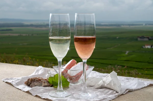 Glasses of white and rose brut champagne sparkling wine and examples of vineyard soils, white chalk stones and firestones and view on grand cru vineyards of  Montagne de Reims near Verzenay, Champagne, France