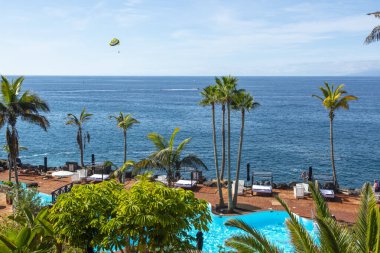 Atlantik Okyanusu kıyısında mavi yüzme havuzu ve palmiye ağaçları olan sahil kulübü, Costa Adeje, Tenerife, İspanya