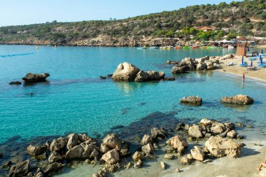 Akdeniz 'in berrak mavi suyu ve Kıbrıs Rum Kesimi' nin Protaras yakınlarındaki kumlu Konnos plajında sarı kayalar