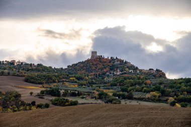 Val d 'Orcia tepelerinde ve Rocco d' Orcia, Toskana, İtalya. Günbatımında sonbaharda selvi ağaçları ve tarlalarla dolu Toskana manzarası