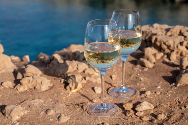 Kıbrıs 'taki Protaras turistik kasabası yakınlarındaki mavi deniz koyunda iki bardak beyaz şarap servis ediliyor.