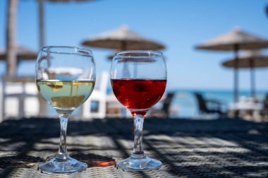 Soğuk gül ve beyaz şarap içmek güneşli kumlu sahildeki bar, arka planda mavi deniz suyu, yaz tatili