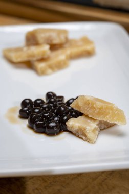 Parma 'dan 72 aylık İtalyan parmegiano-reggiano parmesan peyniri tadı son derece tahıllı ve parçalanmış bir yapısı ve siyah balzamik sirke incileri ile yoğun bir tadı var. Modena' dan DOP, yakın plan.