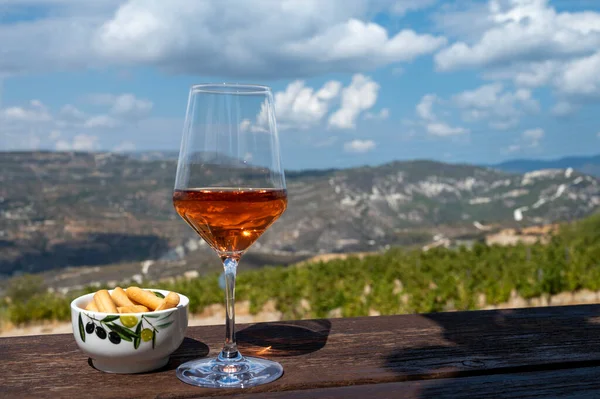 Wine industry of Cyprus island, tasting of rose dry wine on winery with view on vineyards and south slopes of Troodos mountain range in sunny day