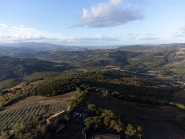 Val d 'Orcia tepelerinde Bagno Vignoni, Toskana, İtalya yakınlarında. Selvi ağaçları, üzüm bağları, ormanlar ve bulutlu sonbaharda sürülen tarlalarla Toskana manzarası.