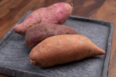 Renkli kök sebzeler pembe, mor ve turuncu organik tatlı patatesler yakın çekim