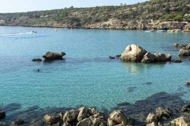 Akdeniz 'in berrak mavi suyu ve Kıbrıs Rum Kesimi' nin Protaras yakınlarındaki kumlu Konnos plajında sarı kayalar