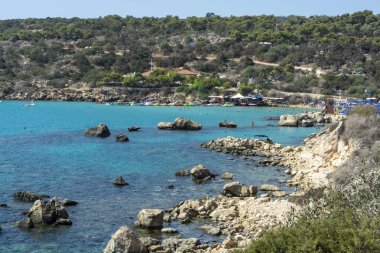 Akdeniz 'in berrak mavi suyu ve Kıbrıs Rum Kesimi' nin Protaras yakınlarındaki kumlu Konnos plajında sarı kayalar