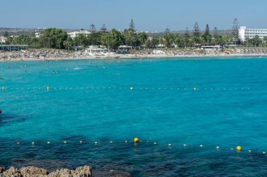 Kıbrıs Rum Kesimi 'nin Ayia Napa kentindeki beyaz kumlu Nissi plajında Akdeniz' in berrak mavi suyu