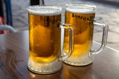 Gün batımında dışarıda servis edilen soğuk biralı iki bardak.