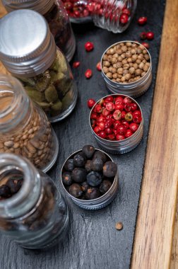 Küçük şişelerdeki profesyonel cin baharatları, pembe biber, amber çiçekleri, ardıç meyveleri, kakule ve kişniş tohumları.